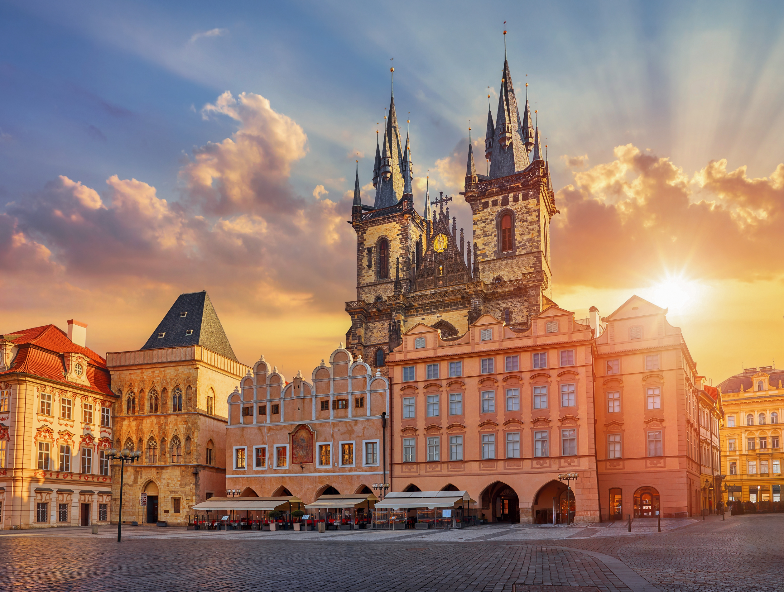 Prague Old Town Square with the iconic Týn Church spires glowing in golden sunset light
