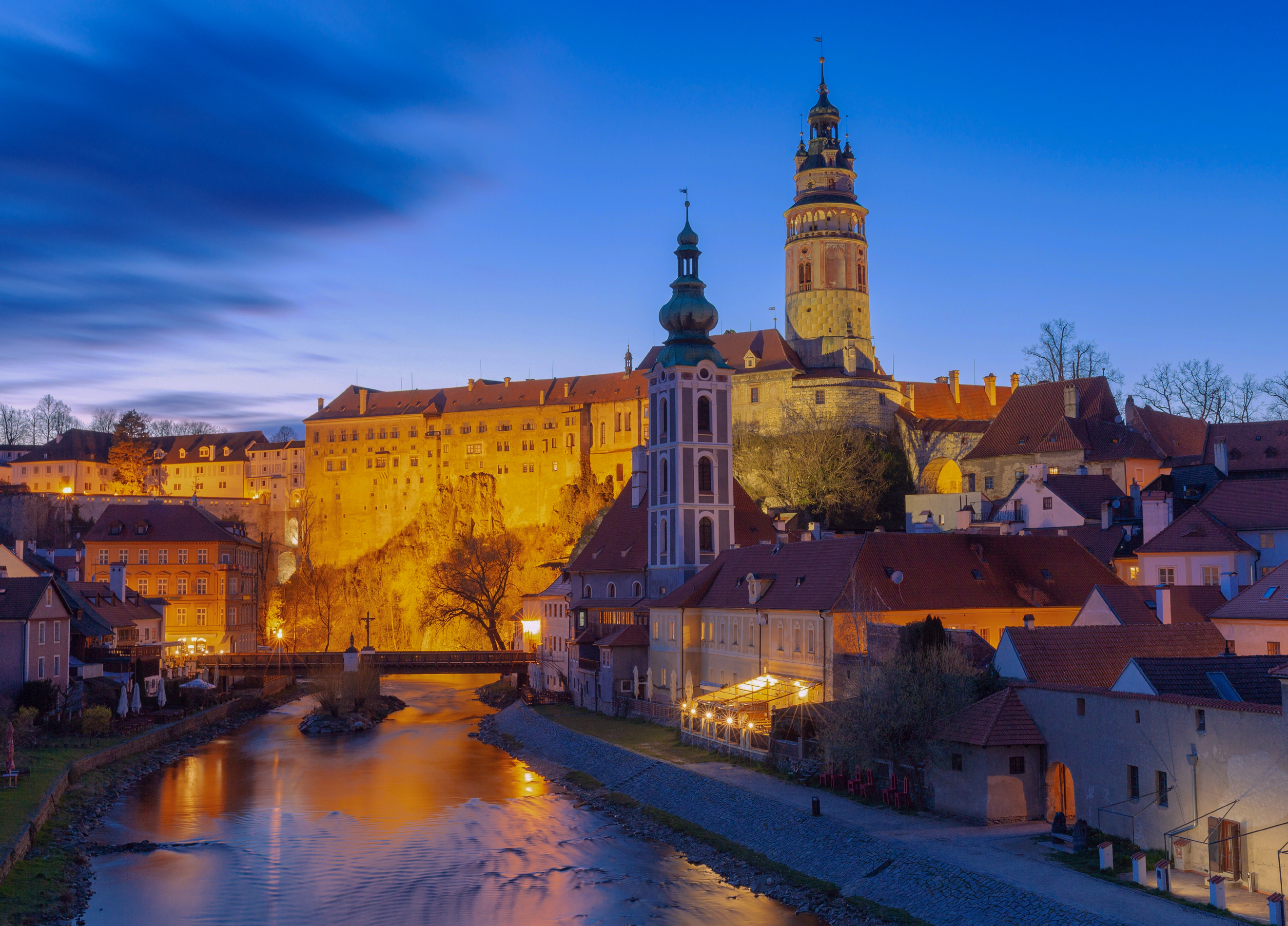 Český Krumlov Castle and old town glowing in the blue hour above the calm waters of the Vltava River.