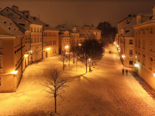 Zimní Kampa v noci s osvětlenými domy a zasněženými ulicemi v Praze