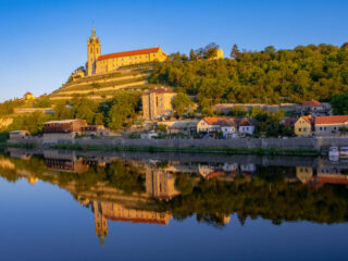 Mělník Castle and vineyards at sunset reflecting in the river near the confluence of the Elbe and Vltava rivers.