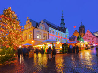 Večerní pirnské vánoční trhy s osvětleným stromem a historickými domy.