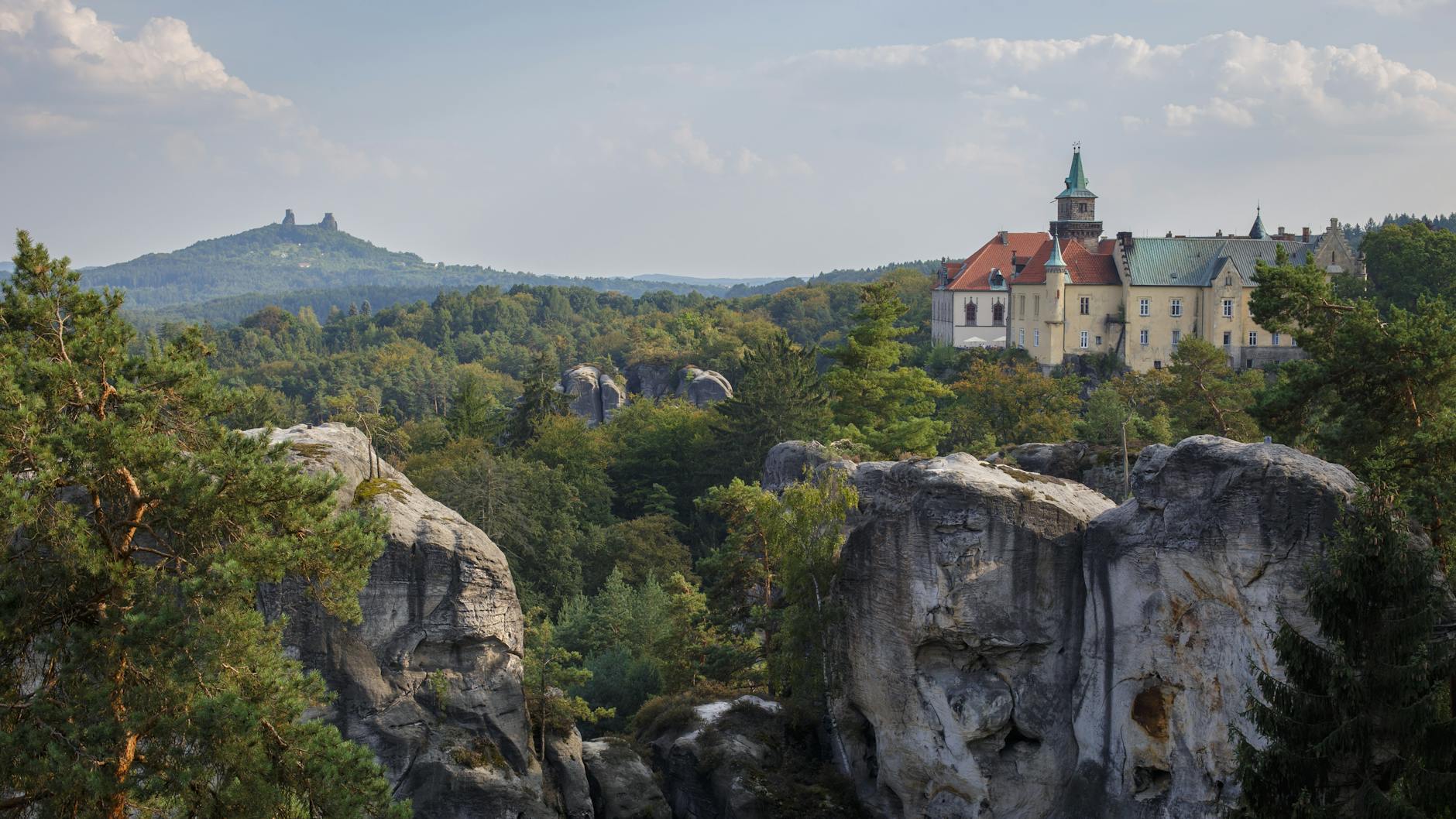 Hrubá Skála chateau perched on sandstone rock formations with Trosky Castle ruins visible in the background