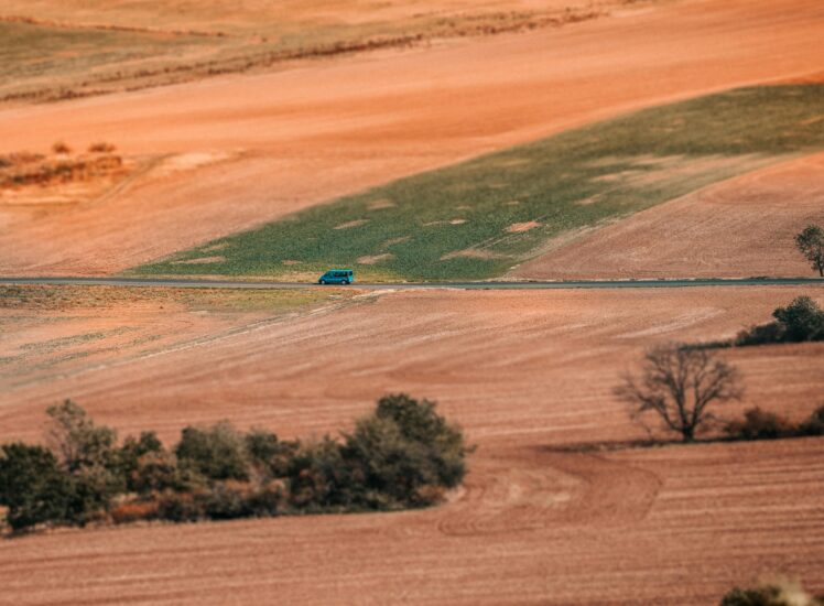Blue car driving through picturesque Czech farmlands on a day trip