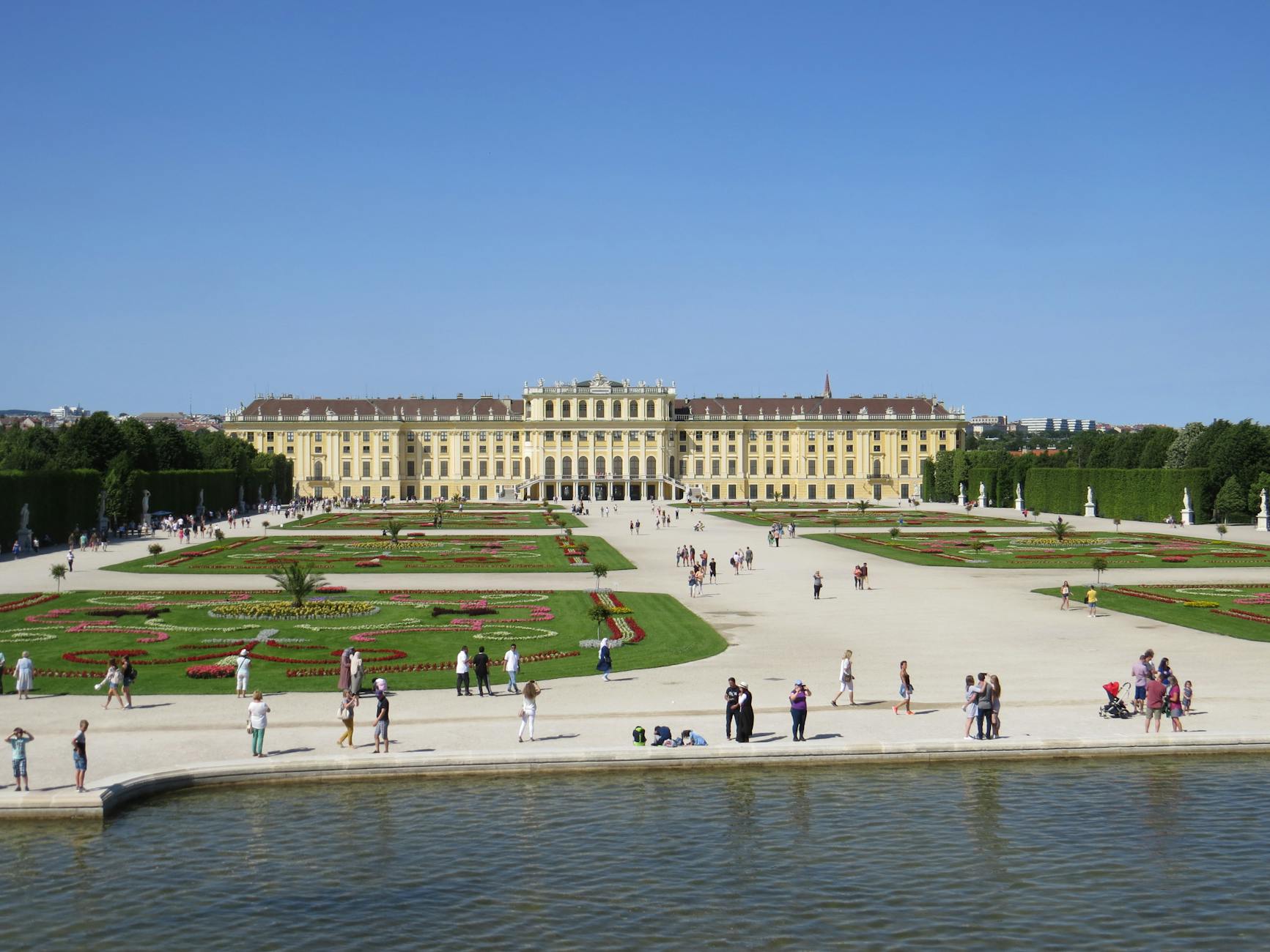 Iconic view of Schönbrunn Palace in Vienna with formal baroque gardens filled with visitors — a highlight of any Vienna day trip from Prague