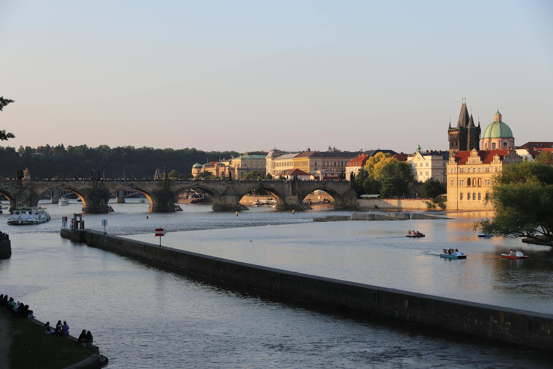 Karlův most a&nbsp;panorama Prahy odrážející se ve Vltavě při západu slunce