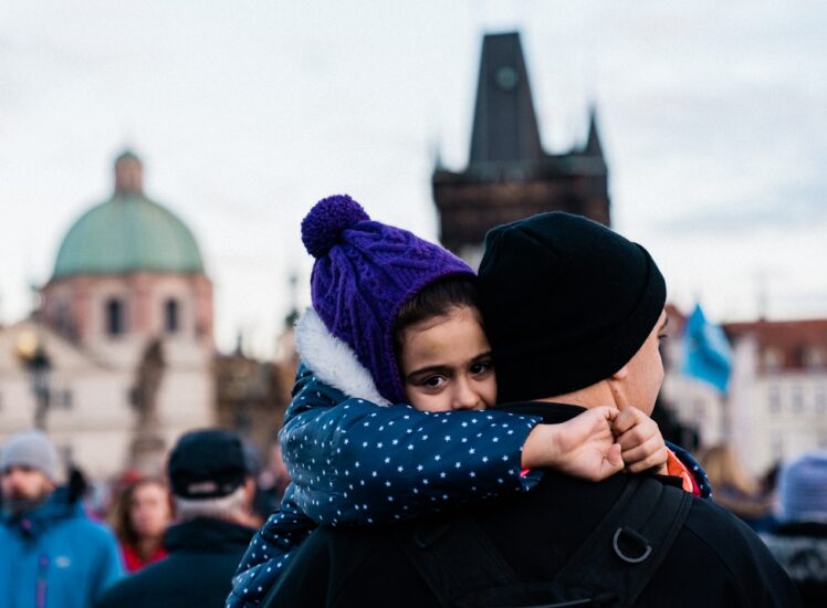 Father carrying his daughter on Charles Bridge in Prague on a sunny day