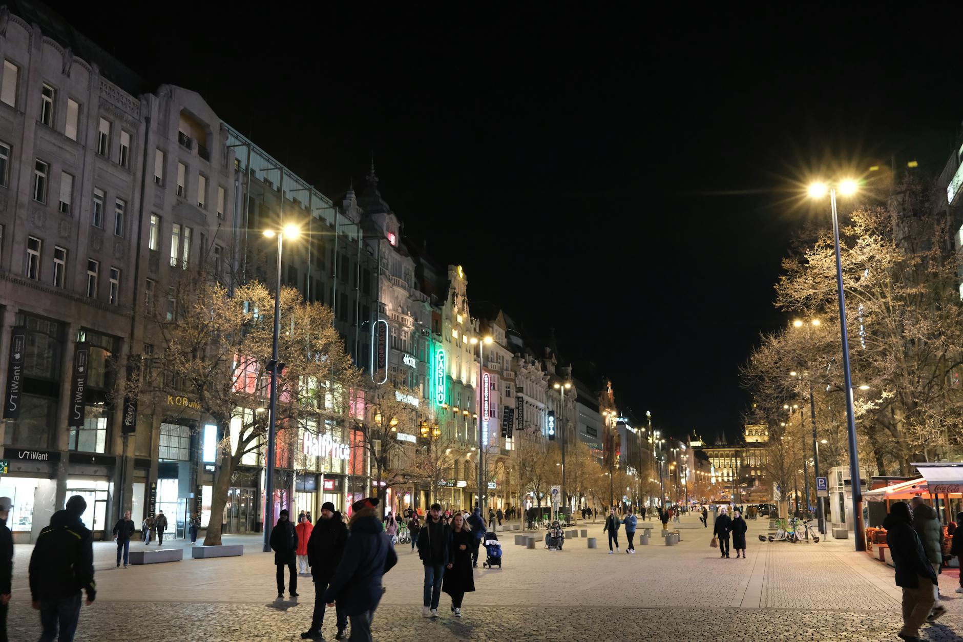 Illuminated streets of Prague at night with pedestrians