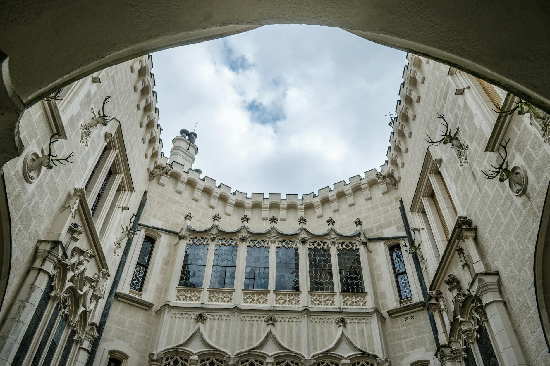 A low-angle view of the intricate gothic architecture of Hluboká Castle in Czechia.